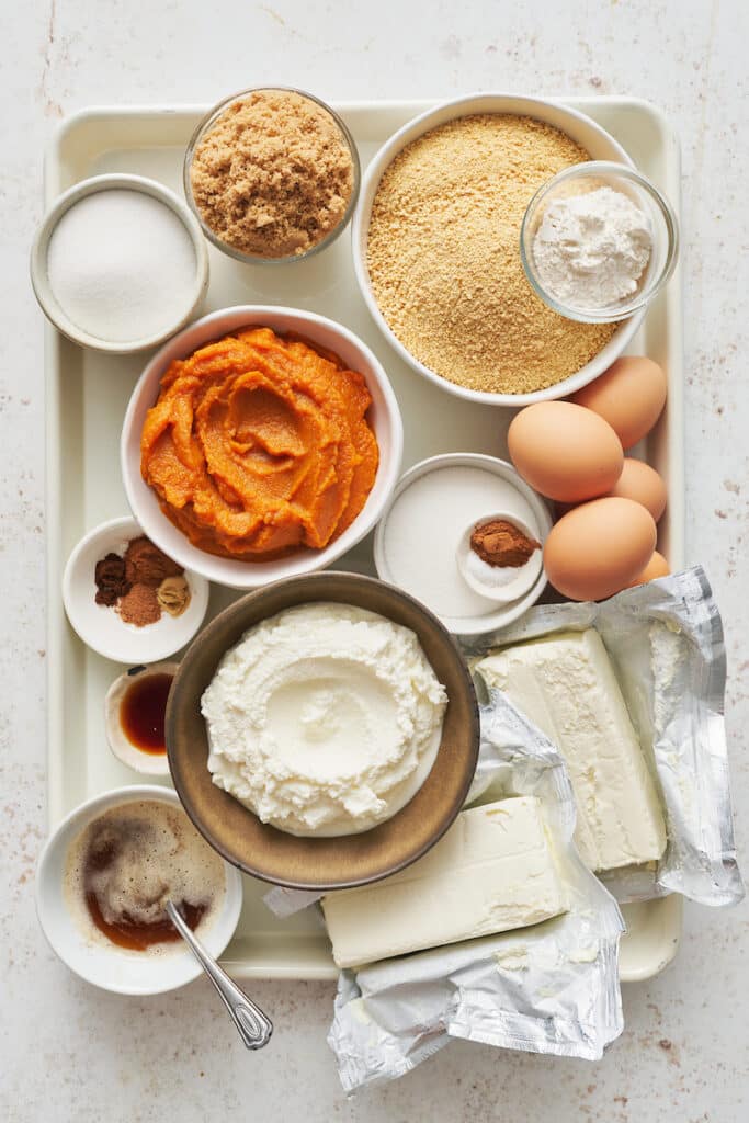 Ingredients for pumpkin cheesecake on a baking sheet. 