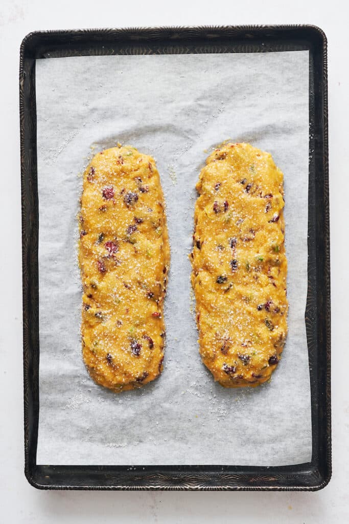 Biscotti loaves shaped on a baking sheet with parchment paper.