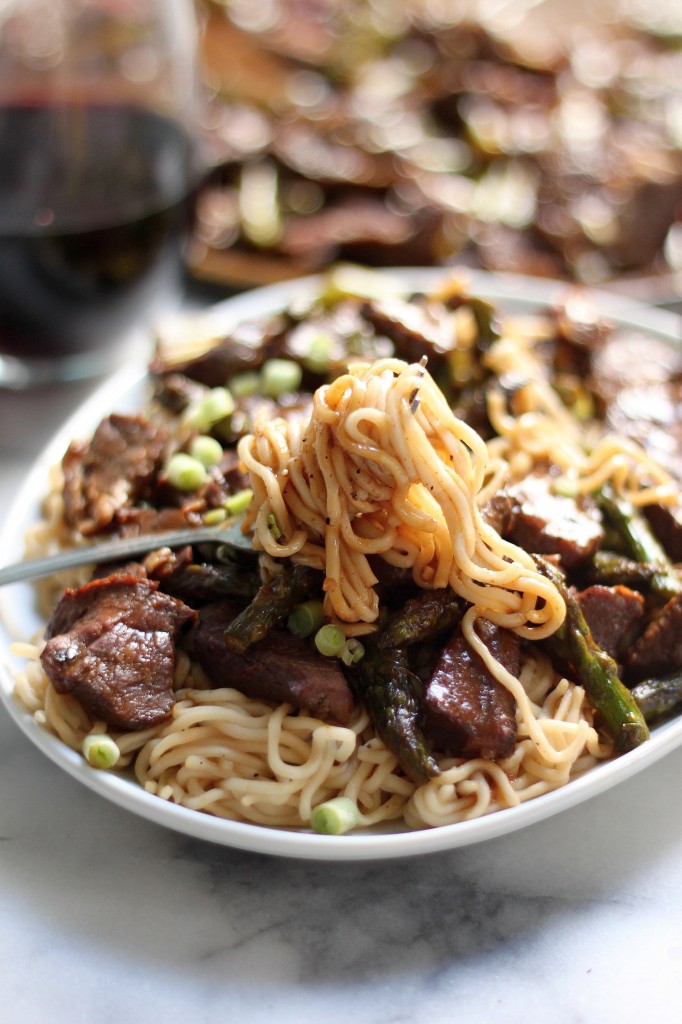  Teriyaki beef ramen noodles with asparagus on white plate. 