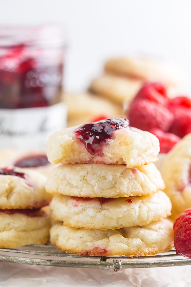 Raspberry thumbprint cookies in a stack on a wire cooling rack.