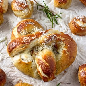 Mozzarella Stuffed Rosemary and Parmesan Soft Pretzels! Made with a simple soft pretzel dough and loaded with fresh herbs and Italian cheese. You're going to love these soft pretzels with cheese inside!