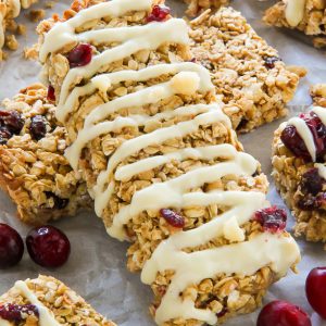 Loaded with cranberries, macadamia nuts, and topped with a sweet drizzle of white chocolate. These homemade granola bars are as easy as they are irresistible!