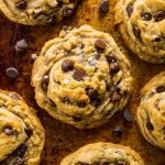 Vegan chocolate chip cookie recipe on a baking sheet with chocolate chips.