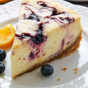 Supremely smooth and creamy homemade Lemon cheesecake topped with fresh Blueberry swirls. All layered on top of a buttery homemade graham cracker crust.