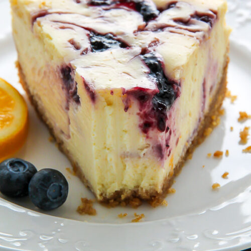Supremely smooth and creamy homemade Lemon cheesecake topped with fresh Blueberry swirls. All layered on top of a buttery homemade graham cracker crust.