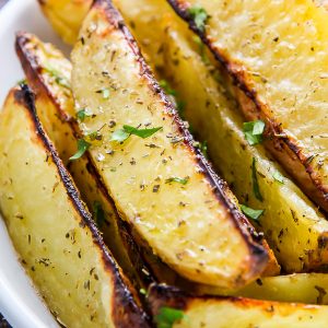 Extra crispy oven baked potato wedges flavored with garlic and herbs. Bet you can't eat just one!