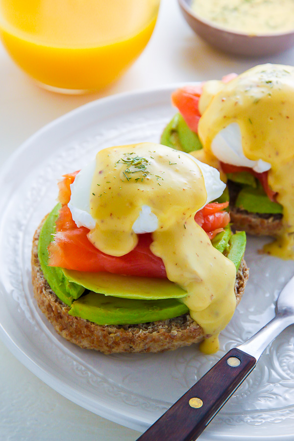 Smoked Salmon and Avocado Eggs Benedict with hollandaise sauce and dill on top.