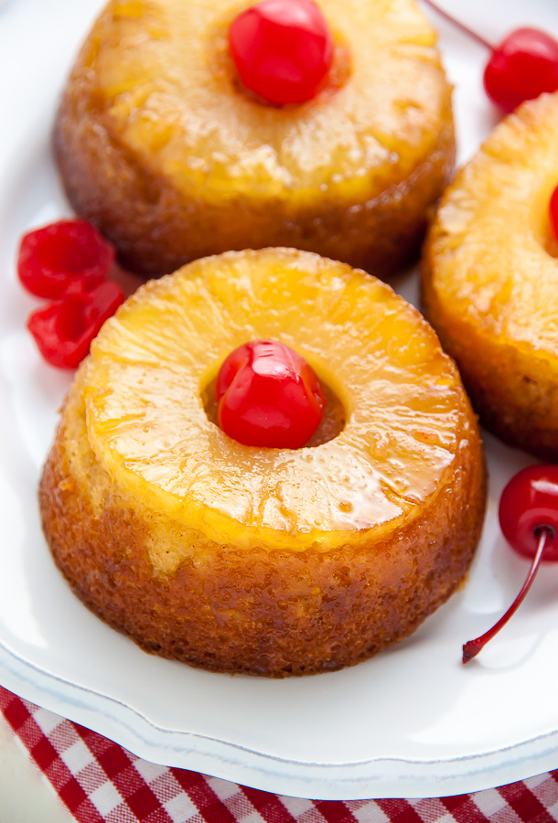 Mini Pineapple Upside-Down Cakes on white plate with cherries. 