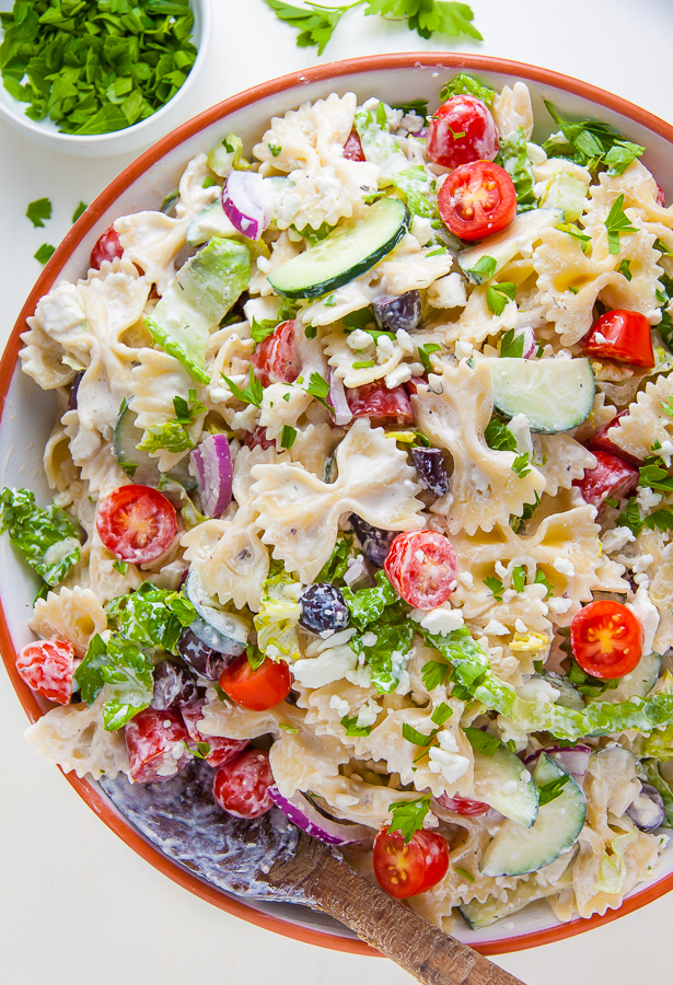 Creamy Greek-Style Pasta Salad in red rimmed bowl. 