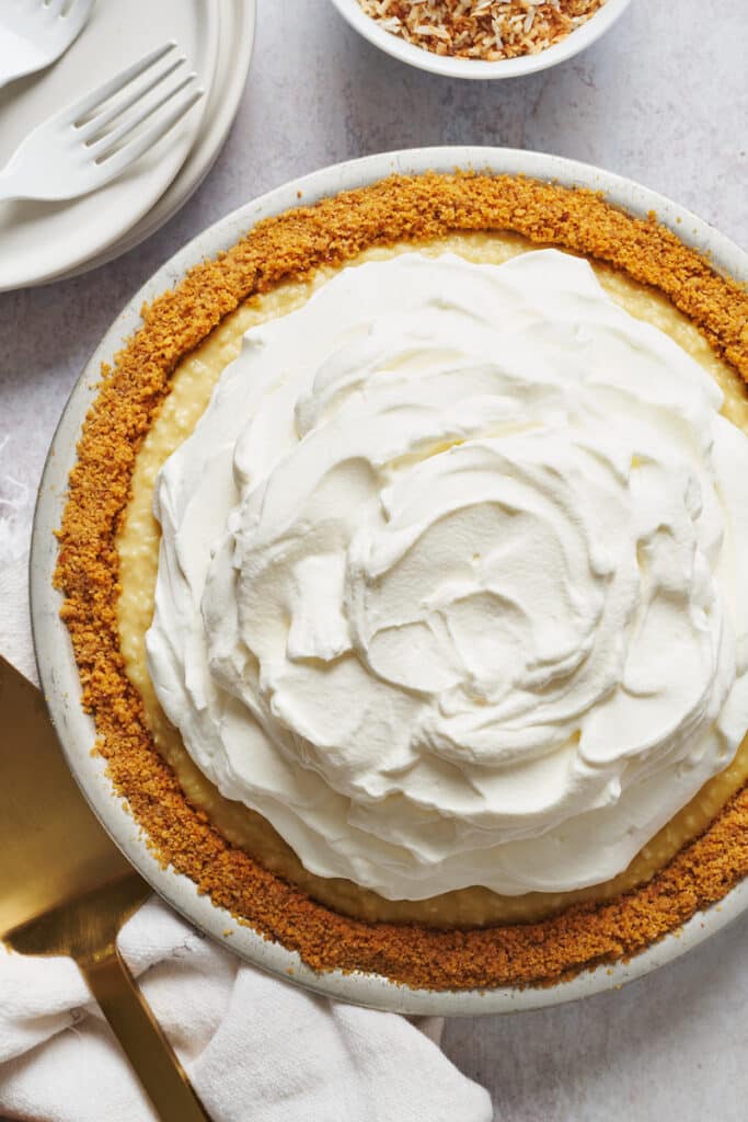 Graham cracker crust filled with creamy coconut filling and topped with homemade whipped cream for coconut cream pie recipe.