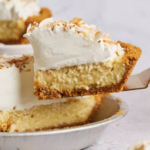 Slice of creamy coconut cream pie being lifted out of the pie plate.