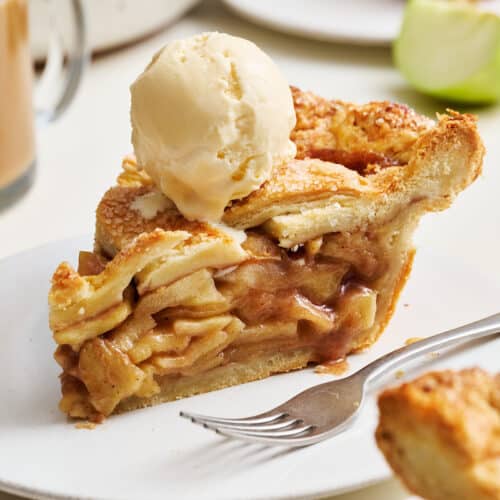 Slice of apple pie on a plate with ice cream on top.