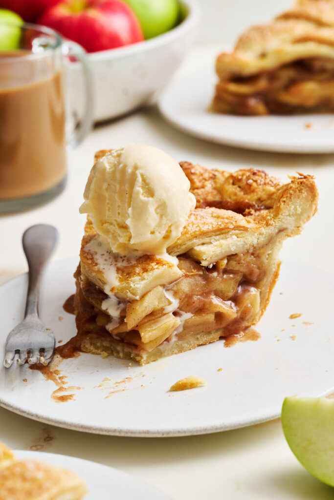 Slice of apple pie with ice cream on top.