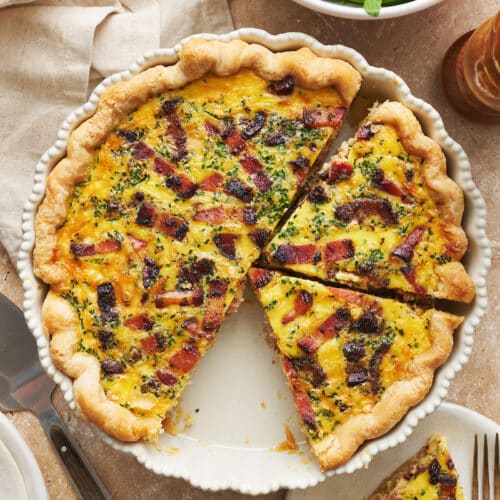 Quiche Lorraine in a pie plate with a simple green salad on the side.