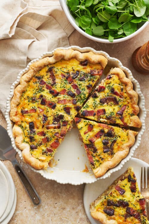 Quiche Lorraine in a pie plate with a simple green salad on the side.