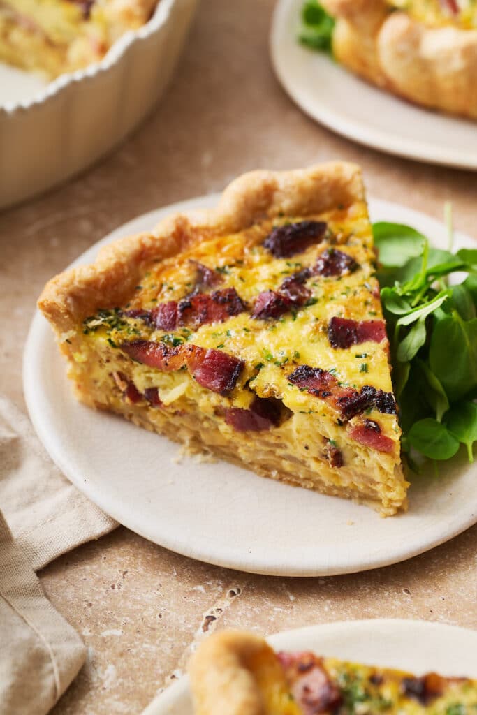 Slice of Quiche Lorraine on a plate with a green salad. 