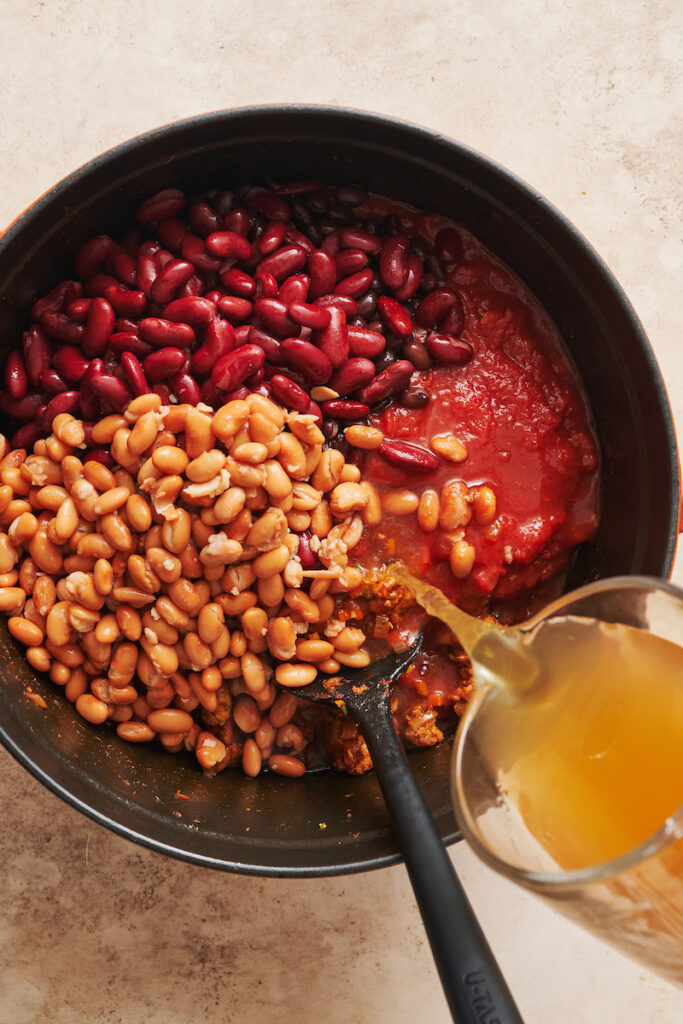 Adding the kidney beans and vegetable broth into the turkey chili.