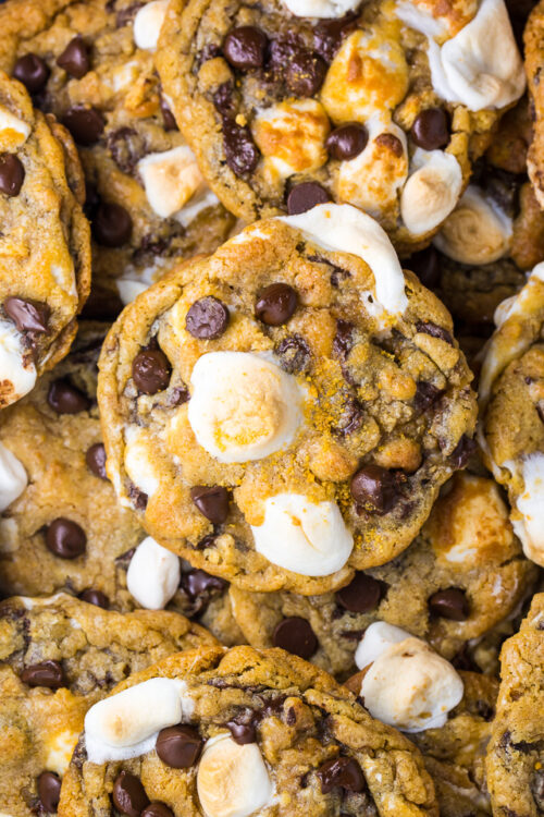 S'mores Chocolate Chip Cookies piled on top of each other with mini marshmallows on top.