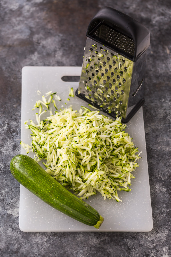 Shredded zucchini on a white cutting board.