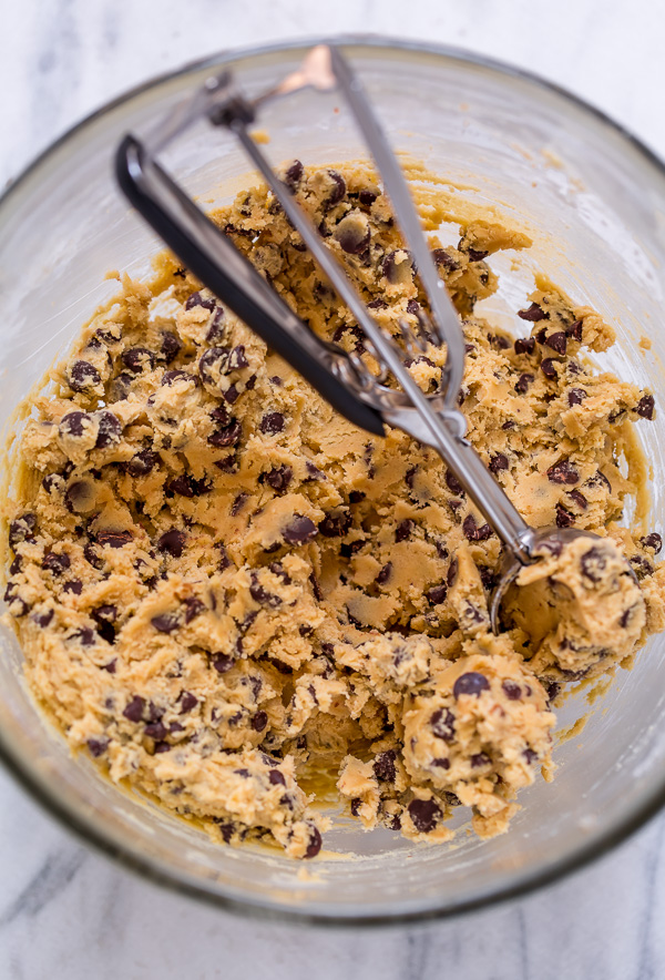 Cookie dough in mixing bowl with cookie scoop.