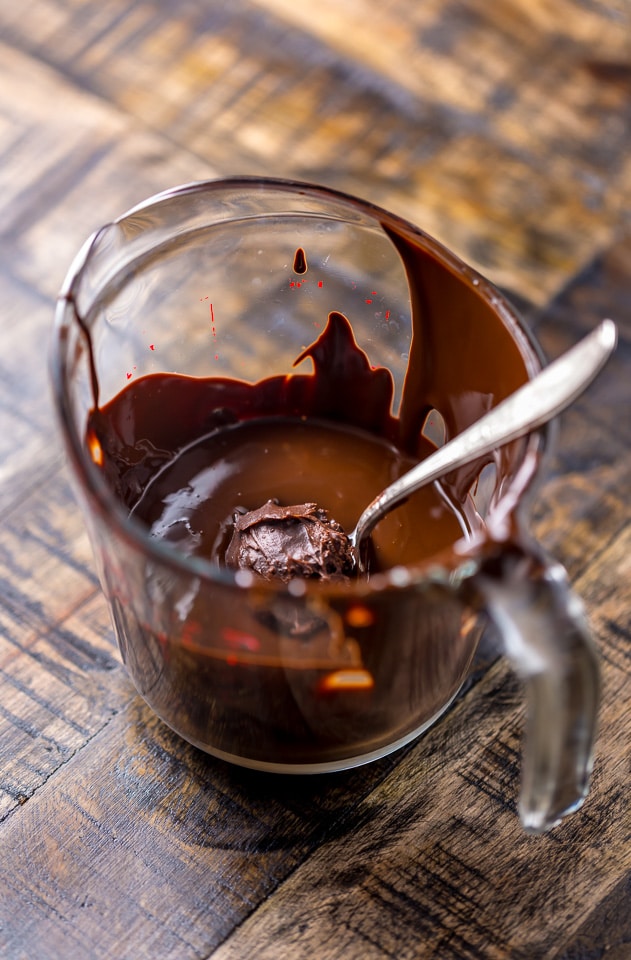 Chocolate truffle being dipping in tempered chocolate. 