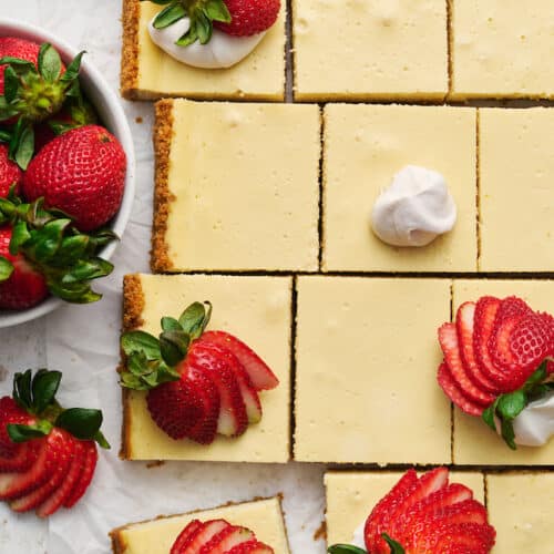 New York-Style Cheesecake Bars have a classic cheesecake filling and crunchy graham cracker crust! Full-fat cream cheese and sour cream are the secret to an ultra creamy cheesecake filling! Cut into squares and top with whipped cream and strawberries for a crowd-pleasing dessert everyone will love. 