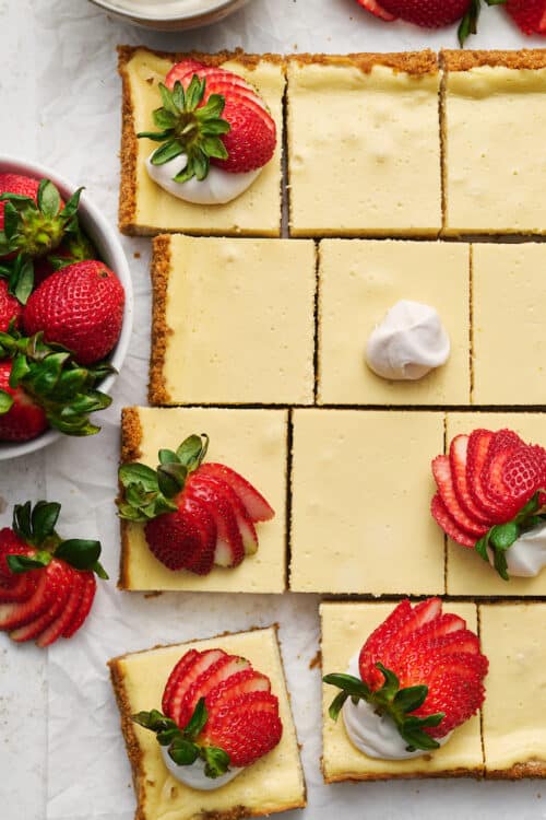 New York-Style Cheesecake Bars have a classic cheesecake filling and crunchy graham cracker crust! Full-fat cream cheese and sour cream are the secret to an ultra creamy cheesecake filling! Cut into squares and top with whipped cream and strawberries for a crowd-pleasing dessert everyone will love. 