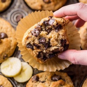 Banana chocolate chip muffins in a baking pan with a bite taken out.