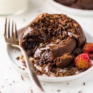 Lava cake on a white plate with a bite taken out of it.