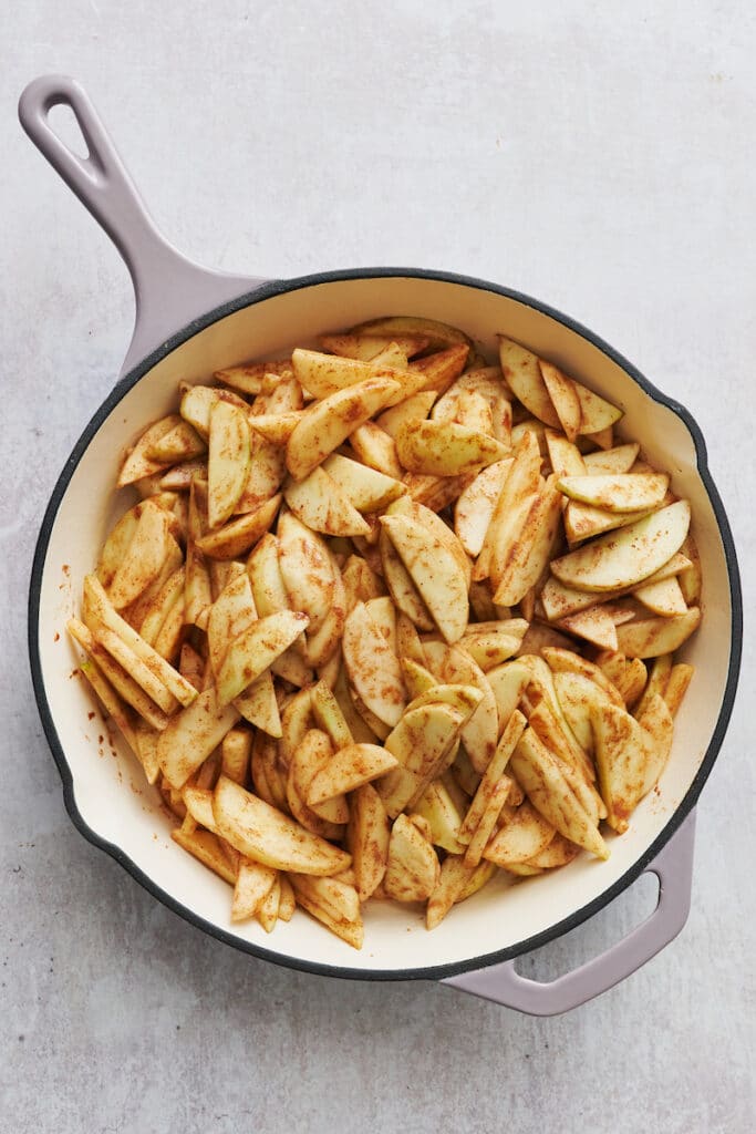 A skillet of apple filling topped with crumbly topping for apple crisp recipe.