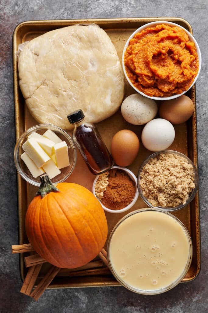 Ingredients for pumpkin pie recipe on a large baking sheet.