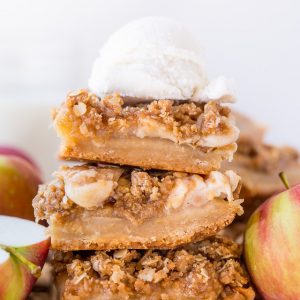 Apple pie bars in a stack with ice cream on top.