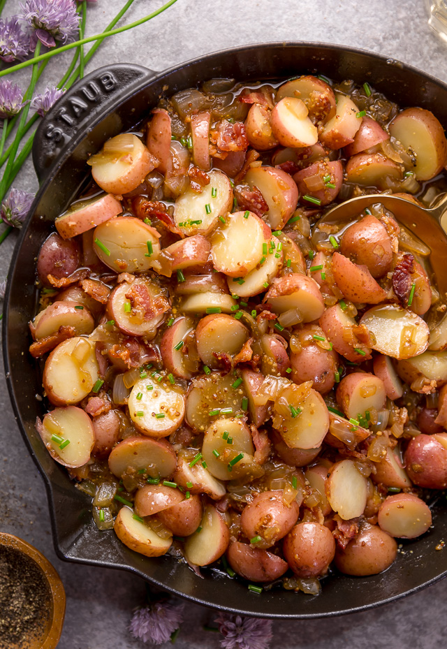 I had my first taste of German Potato Salad 7 years ago and it was love at first bite! It's made with baby red potatoes, yellow onion, and an apple cider vinegar dressing consisting of salt, pepper, mustard, and sugar. And then it's topped with cooked bacon, chopped chives, and a drizzle of olive oil! This potato salad is served warm and makes a great side dish! #potatosalad #Germanpotatosalad 
