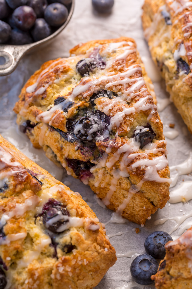 These Classic Bakery-Style Blueberry Scones are sweet, buttery, and exploding with fresh blueberries! Topped with sparkling coarse sugar and a sweet vanilla glaze, these are perfect for breakfast or brunch! Even scone haters love this recipe!