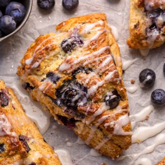 These Classic Bakery-Style Blueberry Scones are sweet, buttery, and exploding with fresh blueberries! Topped with sparkling coarse sugar and a sweet vanilla glaze, these are perfect for breakfast or brunch! Even scone haters love this recipe!
