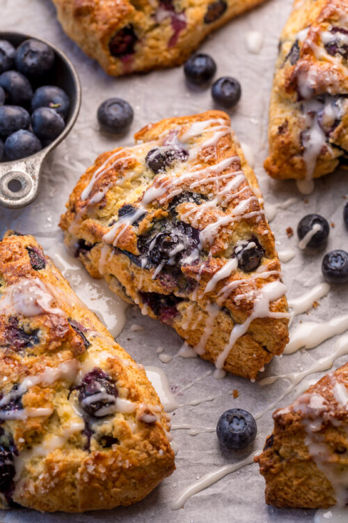 These Classic Bakery-Style Blueberry Scones are sweet, buttery, and exploding with fresh blueberries! Topped with sparkling coarse sugar and a sweet vanilla glaze, these are perfect for breakfast or brunch! Even scone haters love this recipe!