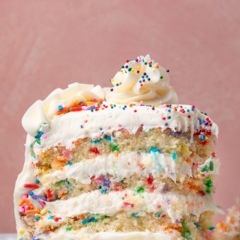 Slice of funfetti cake with sprinkles on the sides and on top of the cake.