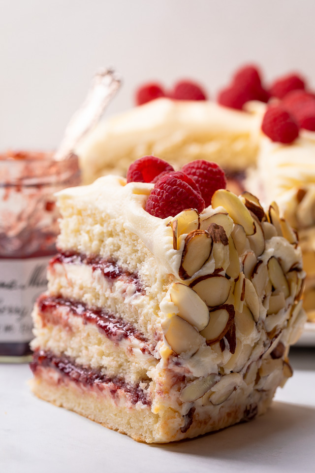 This Almond Raspberry Cake with White Chocolate Amaretto Buttercream Frosting is a total showstopper! Featuring four layers of light and fluffy almond cake, raspberry filling, and creamy white chocolate amaretto cream, this cake is decadently sweet! A must try if you love raspberry almond desserts!