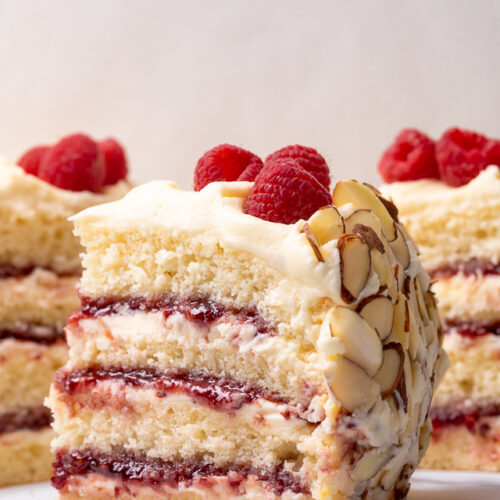 This Almond Raspberry Cake with White Chocolate Amaretto Buttercream Frosting is a total showstopper! Featuring four layers of light and fluffy almond cake, raspberry filling, and creamy white chocolate amaretto cream, this cake is decadently sweet! A must try if you love raspberry almond desserts!
