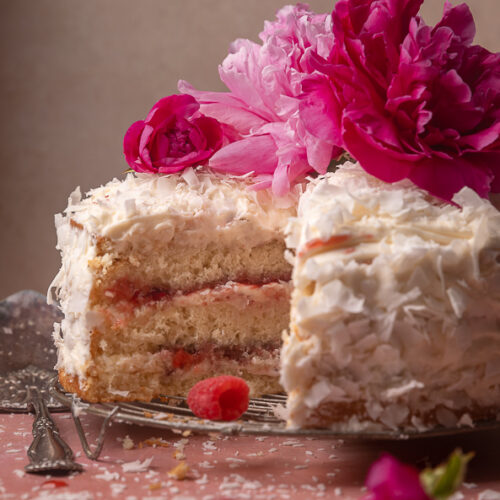 This ultra moist coconut cake is layered with raspberry filling and creamy coconut cream cheese frosting, and then coated in a thick layer of shredded coconut! Make it a showstopper by decorating with edible flowers or fresh raspberries. A must try for raspberry coconut lovers!