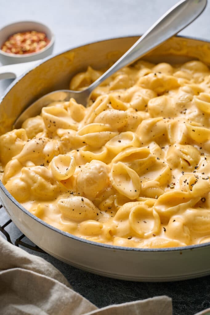 Mac and cheese in a skillet with a spoon. 