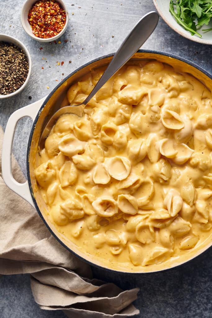 Mac and cheese in a skillet with a serving spoon.