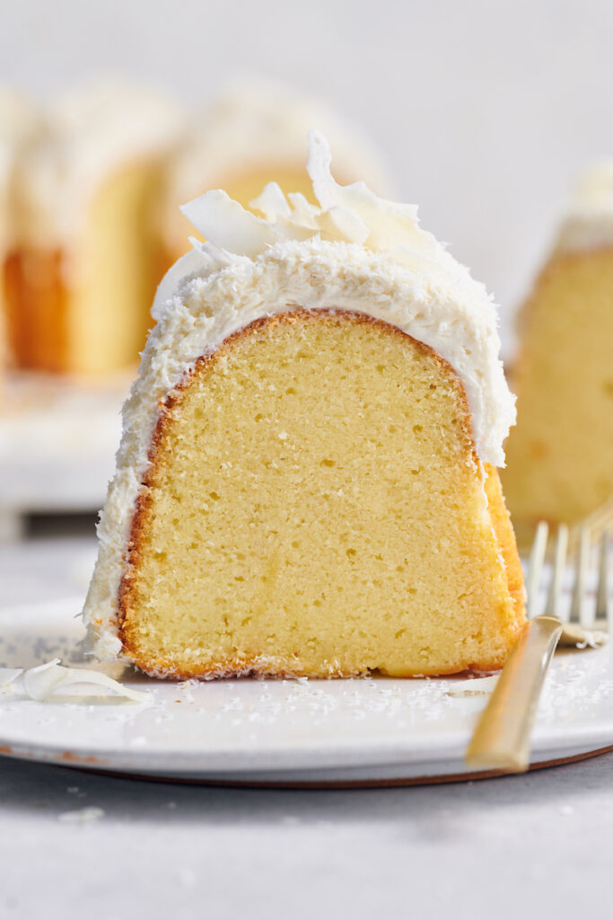 Slice of Tom Cruise coconut cake on a white dessert plate with a fork on the side.