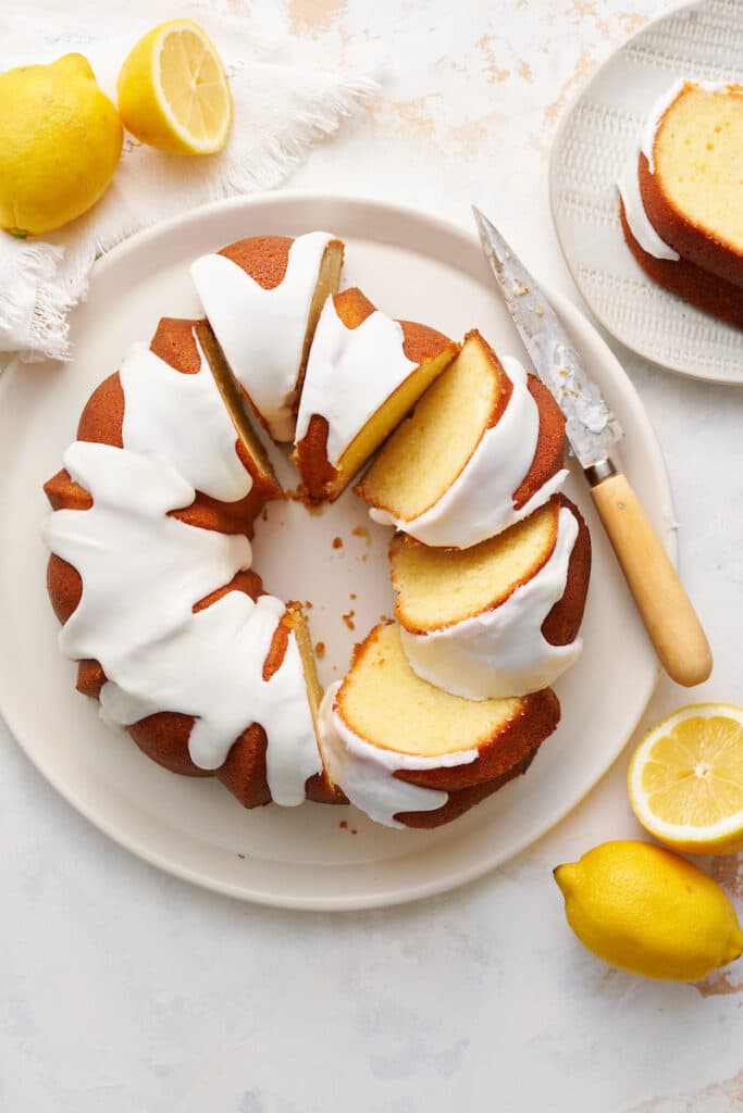 Lemon bundt cake topped with lemon glaze on dessert plate with knife.