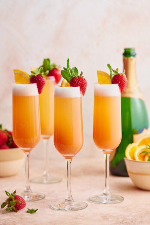 Everyone knows how to make a classic mimosa, so today I'm teaching you how to make my special sunrise strawberry mimosa recipe! Made with strawberry puree, champagne, and fresh squeezed orange juice, these are perfect for brunch! Garnish with mint sprigs, strawberries, and orange slices for an extra pretty presentation!