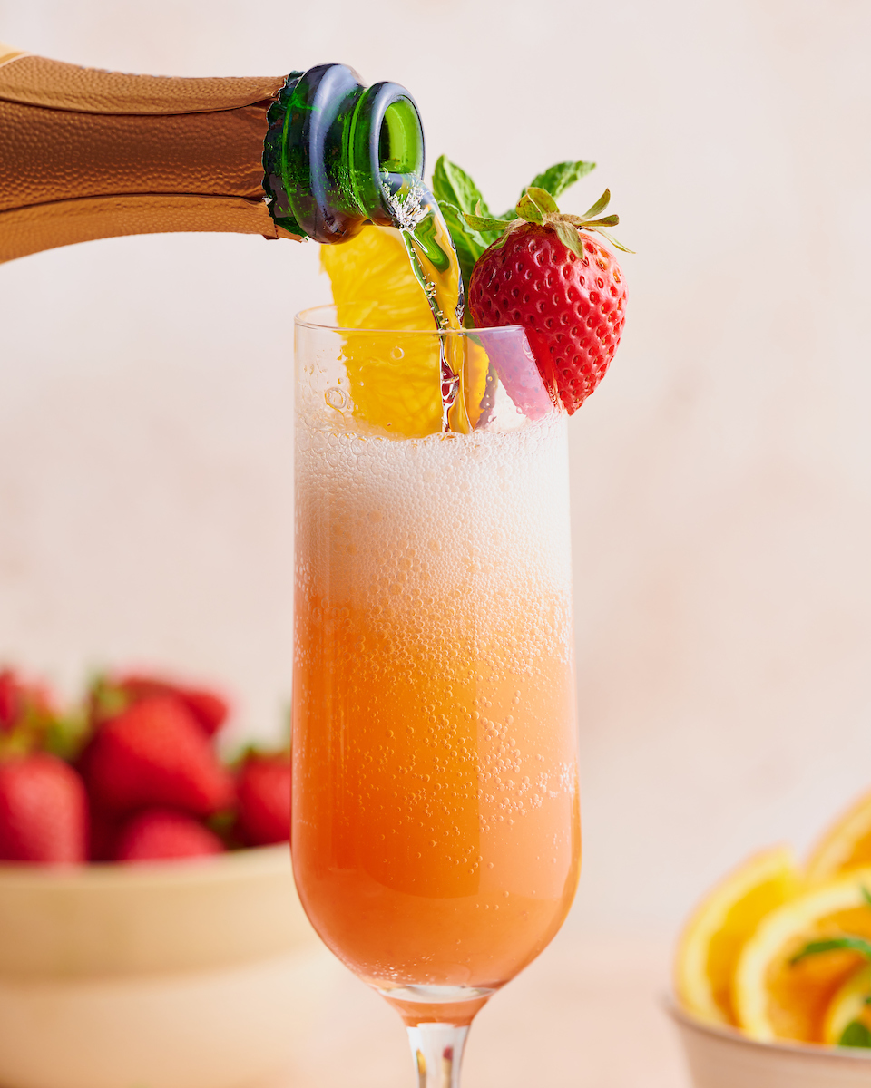 Everyone knows how to make a classic mimosa, so today I'm teaching you how to make my special sunrise strawberry mimosa recipe! Made with strawberry puree, champagne, and fresh squeezed orange juice, these are perfect for brunch! Garnish with mint sprigs, strawberries, and orange slices for an extra pretty presentation!