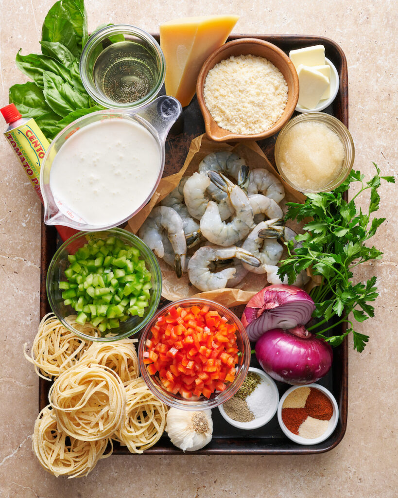 Ingredients for cajun shrimp pasta recipe on a large baking sheet.