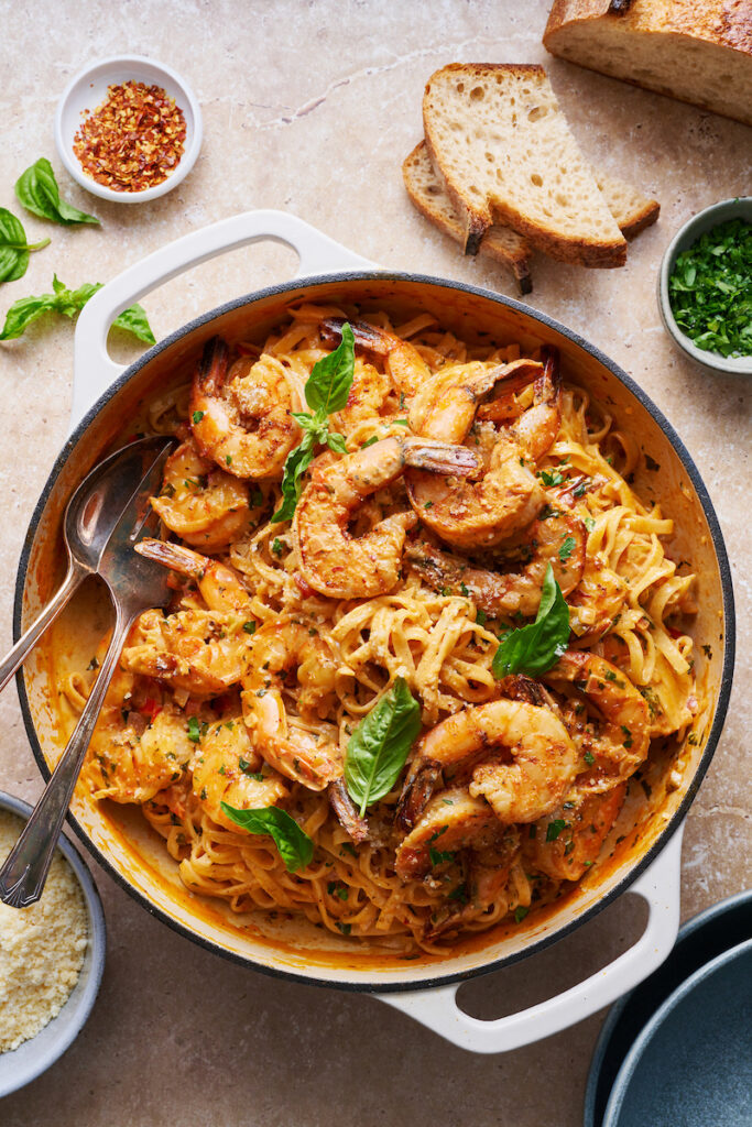 Cajun shrimp pasta topped with juicy shrimp and fresh herbs, served in a white dutch-oven.