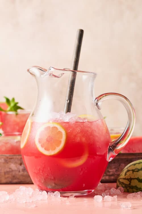 Pitcher full of watermelon lemonade with stirring spoon.