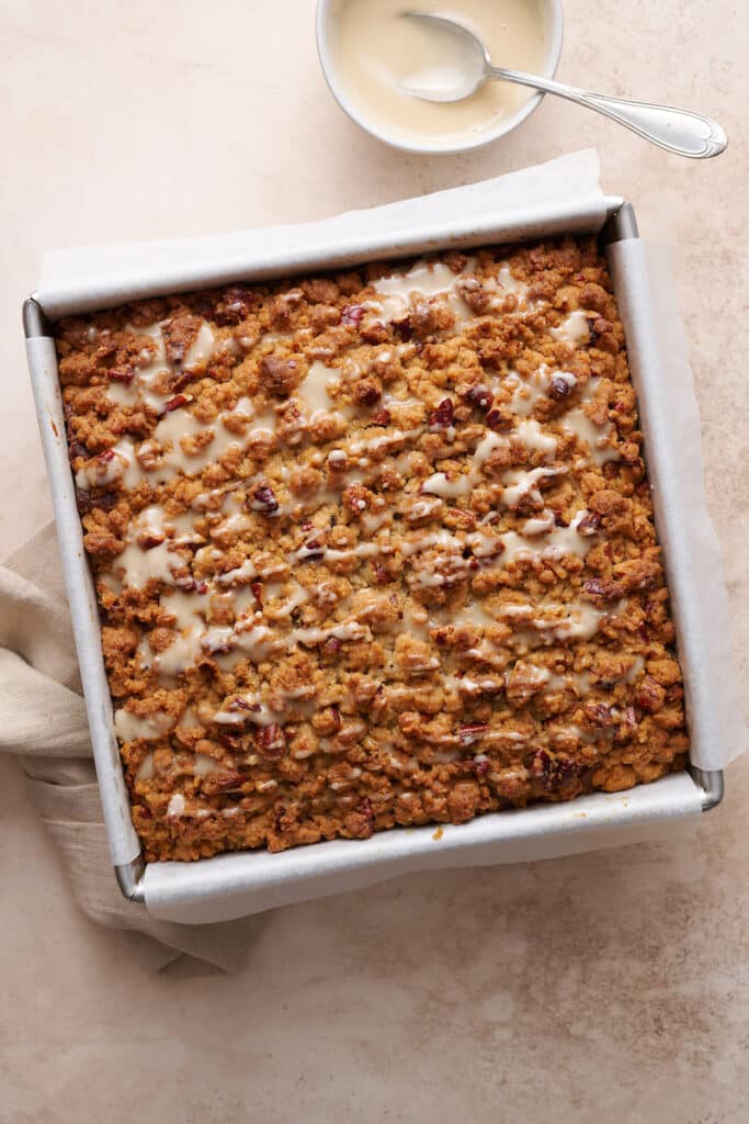 Pumpkin coffee cake in baking pan with vanilla glaze on top.